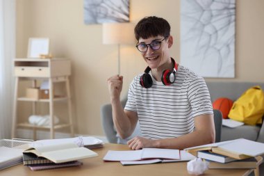 İyi bir sınav sonucunu kutlayan mutlu öğrenci içeride masada.