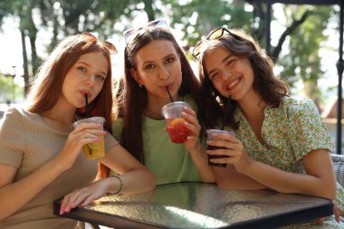 Arkadaşlar açık kafede içeceklerin tadını çıkarıyorlar.