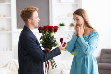 Nişan yüzüğü ve gül buketi olan bir adam mutlu kız arkadaşına evlenme teklif ediyor.