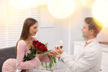 Nişan yüzüğü ve gül buketi olan bir adam mutlu kız arkadaşına evlenme teklif ediyor. Bokeh etkisi