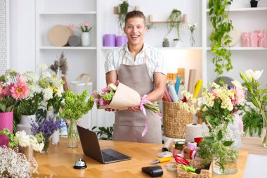 Dükkandaki ahşap masada çalışan bir buket çiçekli profesyonel çiçekçi.