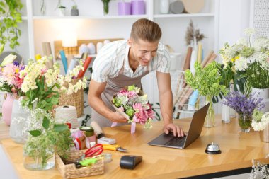 Dükkandaki ahşap masada çalışan bir buket çiçekli profesyonel çiçekçi.