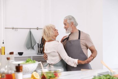 Yaşlı çift mutfakta yemek yaptıktan sonra dans ediyor.