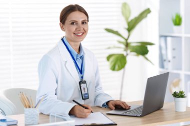 Teletıp. Doktor içeride bilgisayarla hastayla görüntülü konuşma yaparken not alıyor.