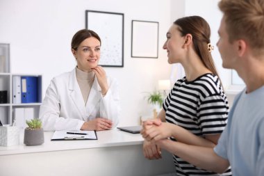 Tüp bebek (tüp bebek). Üreme kliniğindeki doktorla olan randevuda el ele tutuşan çift