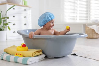 Evde şapkalı şirin bir bebek banyo yapıyor.