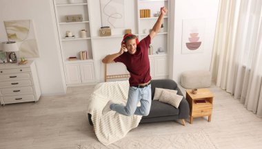 Evde müzik dinlerken zıplayan mutlu bir adam.