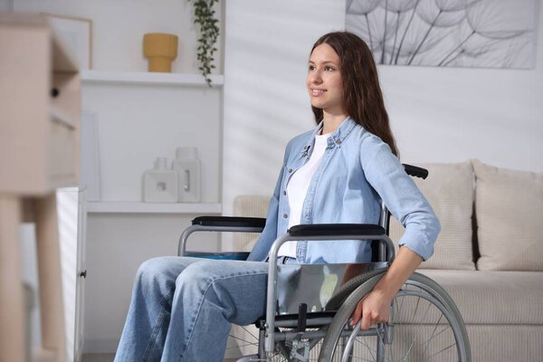 Smiling teenage girl in wheelchair at home