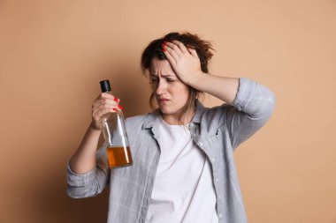 Bir şişe alkollü kadın bej arka planda akşamdan kalma.
