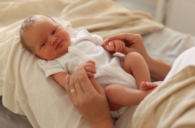 Anne yeni doğmuş bebeğiyle evde, yatakta, yakın plan.