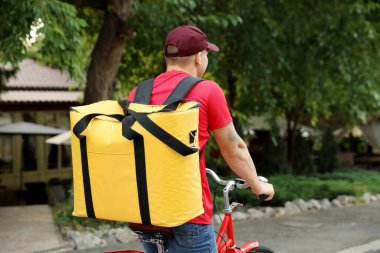 Termo çantalı kurye dışarıda bisiklet sürüyor, mesaj için yer var. Yemek dağıtım servisi.