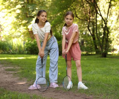 Parkta poz veren badminton raketleri olan şirin küçük kızlar.