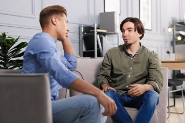 Ofisteki koltuklarda sohbet eden meslektaşlar.