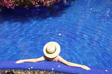 Güneşli bir günde, açık havada havuzda hasır şapkalı bir kız.