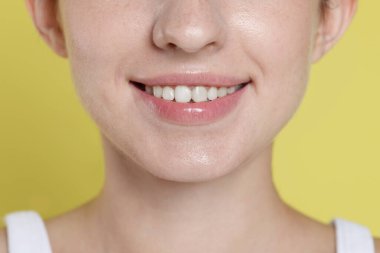 Gülümseyen kadın diş hizalama tedavisinden sonra sarı arka planda, yakın plan