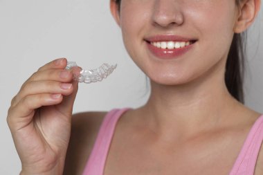 Gri arka planda diş hizalayan gülümseyen kadın, yakın plan.