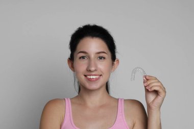 Gri arka planda diş hizalayan gülümseyen kadın portresi