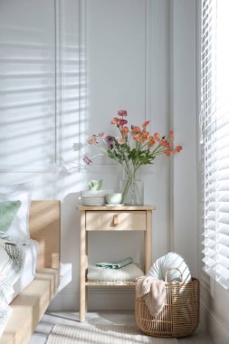 Yatağın yanında farklı dekorları olan bir komodin.