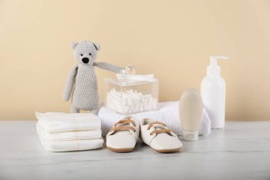 Bej arka planda farklı bebek aksesuarları ve oyuncak ayı var.