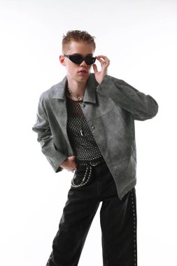 Beyaz arka planda şık ceket ve güneş gözlüğü takan yakışıklı bir genç.