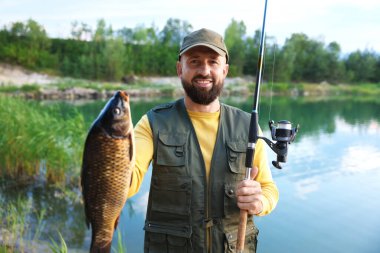 Gülümseyen balıkçılar oltayı tutar ve yazın göl kenarında balık yakalarlar.