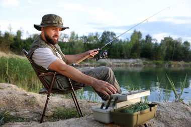 Çubuklu ve diğer ekipmanlı balıkçılar yazın göl kenarında balık tutuyorlar.