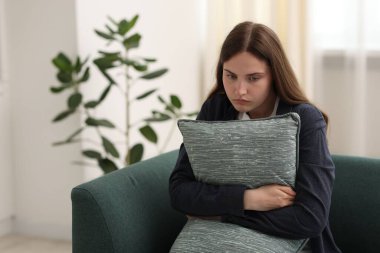 Evdeki kanepede oturan yastıklı üzgün genç kadın, mesaj için yer var.