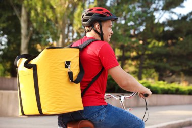Termo çantalı kurye dışarıda bisiklet sürüyor. Yemek dağıtım servisi.
