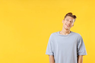 Hayaller gerçek oluyor. Pozitif genç adam sarı arka planda bir şeyler düşünüyor. Metin için boşluk