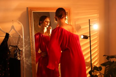 Güzel bir kadın içeride aynanın yanında ruj sürüyor.