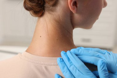 Hastanede genç bir kadının köstebeğini muayene eden doktor, yakın plan.