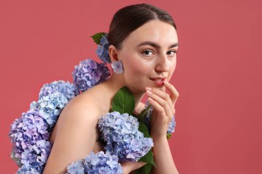Arkaplanda hortensiya çiçekleri olan güzel bir genç kadın.