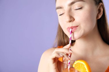 Kadın menekşe arka planında samandan ferahlatıcı içecek içiyor, metin için yer var.