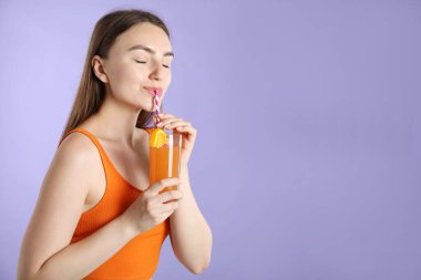 Kadın menekşe arka planında samandan ferahlatıcı içecek içiyor, metin için yer var.