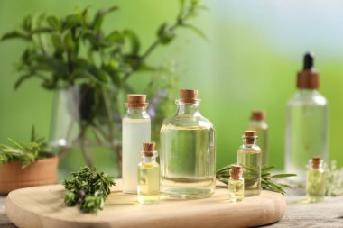 Temel yağlar ve ahşap masa üzerinde farklı otlar, yakın plan.