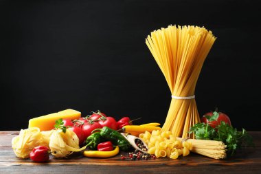 Tahta masadaki farklı makarna ve malzemeler.