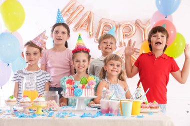 Doğum günü kutlaması. Masadaki çocuklar lezzetli pastalar ve dekoratif odalarda farklı şeyler yiyorlar.