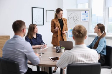 İş koçu ofisteki bir grup insana sunum yapıyor.