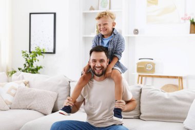 Mutlu baba ve oğlu evdeki kanepede birlikte vakit geçiriyorlar. Aile