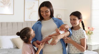 Anne, kızları ve yeni doğmuş bebeğiyle evde.