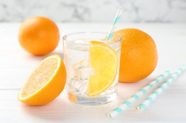 Bardakta portakal dilimli köpüklü su ve beyaz ahşap masada taze meyve, yakın plan.