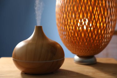 Ahşap masa üzerinde modern aroma lambası, yakın plan.