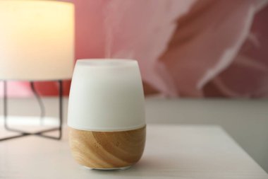 Beyaz ahşap masada modern aroma lambası, yakın plan.