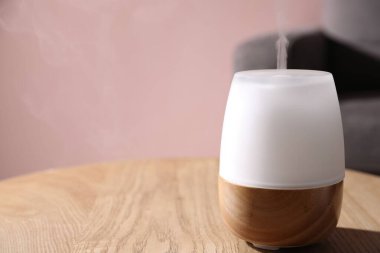 Ahşap masada pembe duvara dayalı şık bir aroma lambası, yakın plan. Metin için boşluk