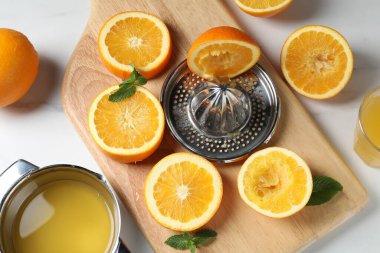 Portakallı sıkma, nane ve taze meyve suyu beyaz masada, düz yerde.