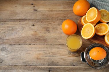 Taze sıkılmış portakal suyu, meyve suyu ve meyve sıkacağı ahşap masada, düz yerde. Metin için boşluk