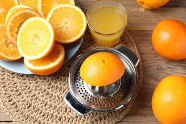 Taze sıkılmış portakal suyu, meyve suyu ve meyve sıkacağı ahşap masada, yukarıda.