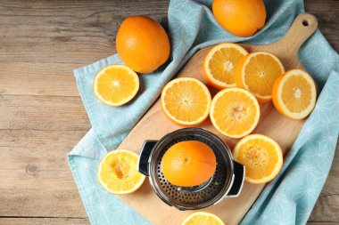Sıkıştırıcı ve portakallar tahta masada, düz yerde. Taze meyve suyu.