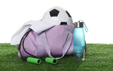 Spor malzemeleri, havlu ve şişe ile şık spor çantası beyaz arka planda yeşil çimenler üzerinde