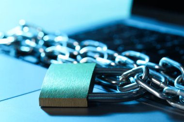 Siber güvenlik. Metal asma kilit, dizüstü bilgisayarında renk ışığı, yakın plan.